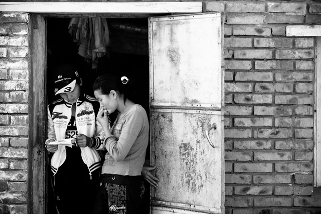 Deux personnes à l’entrée d’une maison en briques, en Mongolie.